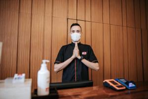 un homme portant un masque alors qu'il se tenait debout dans une pièce dans l'établissement BIZ HOTEL City Center, à Ambon