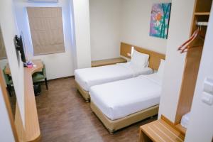 a hotel room with two beds and a desk at BIZ HOTEL City Center in Ambon
