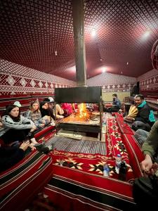 a group of people sitting in a theatre with a fireplace at Bedouin Tours Camp in Wadi Rum