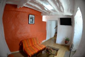 ein Wohnzimmer mit einer orangefarbenen Wand und einem Stuhl in der Unterkunft Hotel Casa Campesina in Cusco