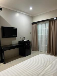 um quarto com uma cama e uma televisão de ecrã plano em Aneeda Inn em Pantai Cenang