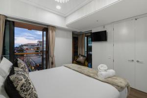 a bedroom with a large bed and a balcony at Extravagant Escape in Auckland