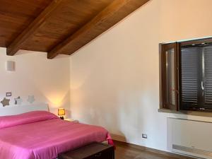 1 dormitorio con cama rosa y ventana en Upupa B&B Casa Vacanza, en Sessa Cilento