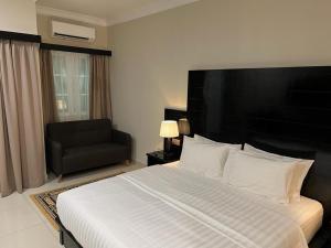 a bedroom with a large bed and a black chair at Aneeda Inn in Pantai Cenang