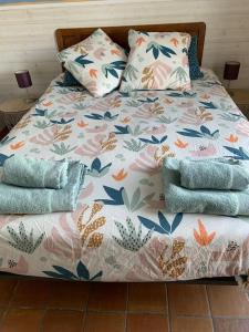 un letto con copriletto e cuscini floreali; di Belle maison spacieuse avec grand jardin a Rongères