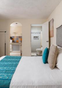 a bedroom with a large white bed and a bathroom at El depa de Acuario in Cancún