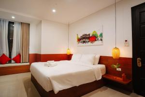 a bedroom with a large bed with white sheets at Hoianese Center Hotel - Truly Hoi An in Hoi An