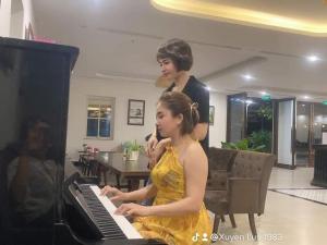 a woman playing a piano with a woman standing behind her at INDOTEL HALONG HOTEL in Ha Long
