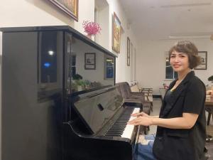 a woman standing in front of a piano at INDOTEL HALONG HOTEL in Ha Long