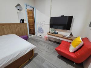 a bedroom with a red chair and a flat screen tv at 海戀初衷文旅 近東大門 in Hualien City