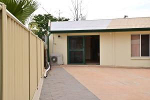 a fence next to a house with a tv at Spacious studio in AliceSprings QueenBed+KSAirbed in Alice Springs