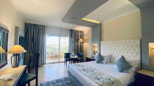 a hotel room with a bed and a desk and a window at Amwaj Oyoun Resort & Casino in Sharm El Sheikh