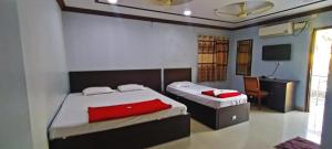 two beds in a room with a desk and a computer at STAYMAKER Hotel Keerthi in Māvalli