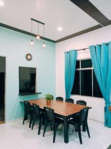 Aila Homestay Pendang في Pendang: غرفة طعام مع طاولة وكراسي خشبية