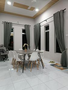 Aila Homestay Pendang في Pendang: غرفة طعام مع طاولة وكراسي خشبية