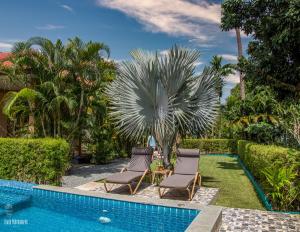 a resort pool with two chairs and a palm tree at Filou Studio Butterfly Pool Access 29 66 in Ko Chang