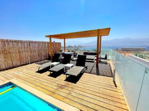 una terraza de madera con sillas y una piscina en villalis, en Eilat