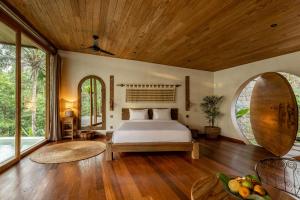 a bedroom with a bed and a large window at Casa Pohon Ubud in Ubud