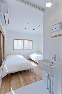 a white bedroom with a bed and a sink at CASA Kamakura Espresso&BED in Kamakura