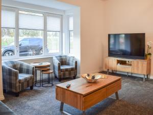 ein Wohnzimmer mit einem Flachbild-TV und einem Tisch in der Unterkunft Pickle House in Newport-On-Tay