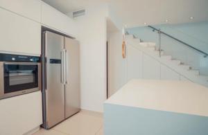 a kitchen with a stainless steel refrigerator and stairs at villalis in Eilat