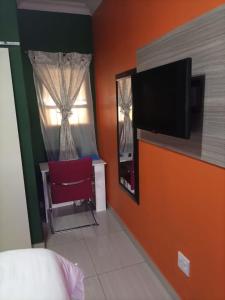 a bedroom with a red chair and a window at Munach Guest Lodge in Benoni