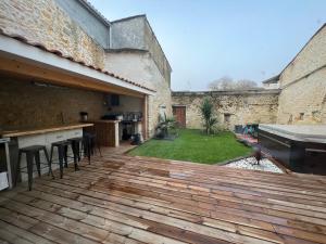 a wooden deck with a kitchen and a backyard at L'auberge médocaine in Castelnau-de-Médoc