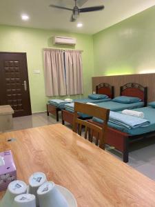 una camera con due letti e un tavolo in legno con un tavolo di 3 Single Bed with Private Bathroom a Kuala Perlis