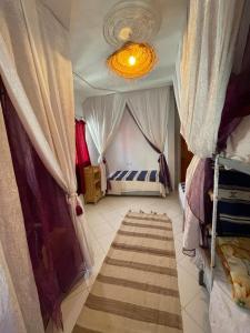 a bedroom with a bed with curtains and a rug at Agachill Surf House in Tamraght Ouzdar +99 photos