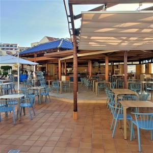 an outdoor patio with tables and blue chairs and tables at Sea View at Santa Maria Aparthotel in Adeje