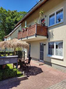 a house with a patio with a table and a balcony at Brandt Ferienwohnungen Jägersberg in Ahlbeck