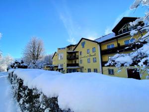 a yellow building with snow in front of it at Gasthof Badl - Bed & Breakfast in Hall in Tirol