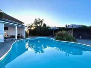 uma piscina com água azul em frente a uma casa em Pelican Motor Inn em Merimbula