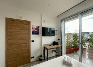 a bedroom with a door and a desk and a television at Bari Airport Rooms in Bari