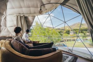 ein Paar auf einer Couch in einem Zimmer mit einem großen Fenster in der Unterkunft Matsukaneya Annex in Zao Onsen