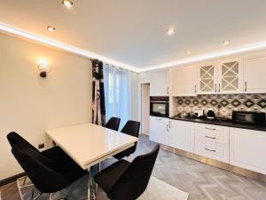 a kitchen with white cabinets and a table and chairs at Апартаменти Стефани in Plovdiv