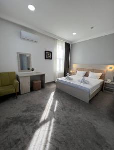 ein Schlafzimmer mit einem großen Bett und einem gelben Stuhl in der Unterkunft South Hotel in Taschkent