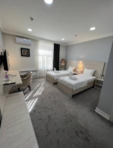 een grote hotelkamer met 2 bedden en een bank bij South Hotel in Tasjkent