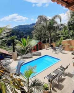a swimming pool on a patio with chaises and chairs at Suítes Sunset in Miguel Pereira