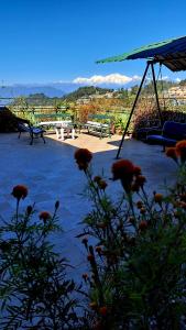 a patio with benches and flowers with mountains in the background at Yuma D Homestay in Darjeeling