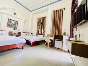 um quarto de hotel com duas camas e uma televisão em Eva Homestay em Hue
