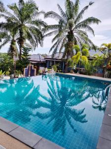 a blue swimming pool with palm trees in the background at Palm Tian Home A7 in Ban Chong Phli
