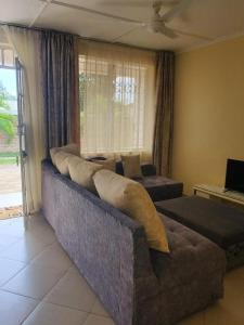 a living room with a large couch and a living room with a tv at Alpha Homes in Kilifi