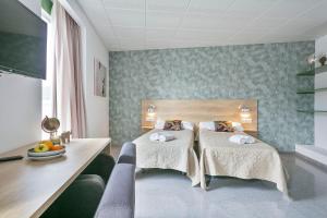 a hotel room with two beds and a desk at Les Begues Apartments in Begues