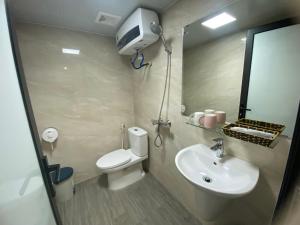 une salle de bain avec toilettes, lavabo et miroir dans l'établissement Minh Hưng Motel, à Hạ Long