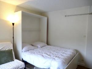 a small bedroom with a white bed and a lamp at Boost Your Immo Néouvielle Barèges PM19 in Barèges