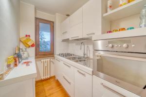 una cocina con armarios blancos y fregadero en Elegante appartamento-100mt dal centro-50mt dalla seggiovia-wifi-parcheggio gratuito, en Sauze dʼOulx