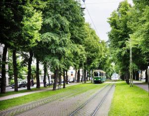 Family city apartment Helsinki في هلسنكي: قطار أخضر يسافر في شارع به أشجار