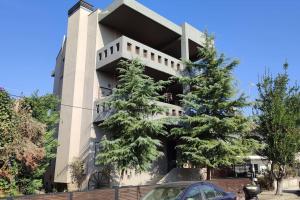 a building with two pine trees in front of it at Lumen 1-bedroom apartment in the heart of Trikala in Tríkala