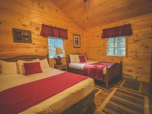 1 Schlafzimmer mit 2 Betten in einem Blockhaus in der Unterkunft Motel Long Lake and Cottages in Long Lake